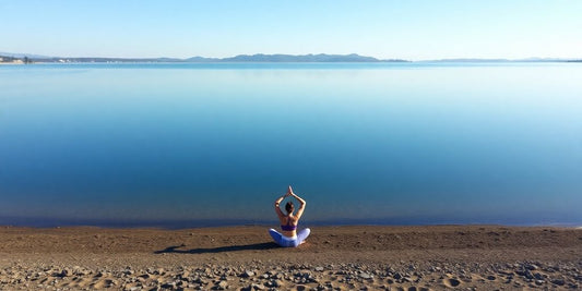 A person practicing yoga by a tranquil lake.