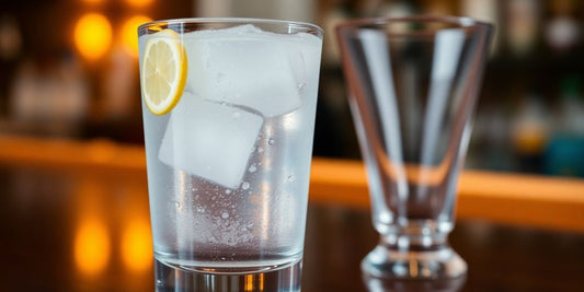 Glass of water beside an empty cocktail glass.