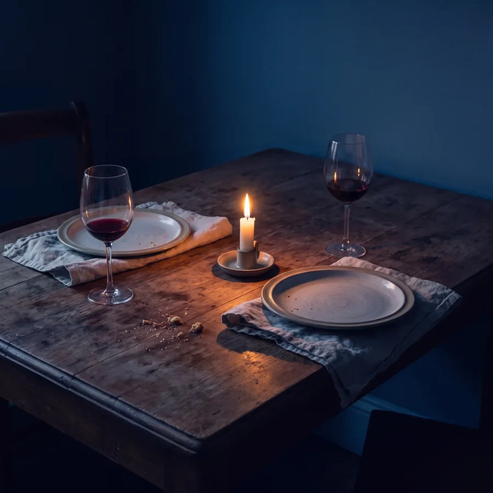 A dinner table after the meal, with two wine glasses and a low candle