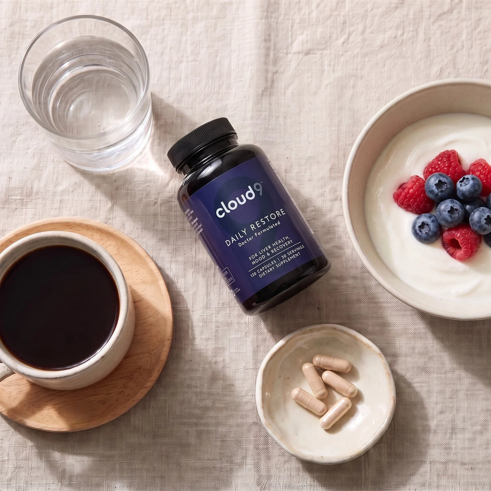 Daily Restore on a breakfast table with coffee, yogurt and berries, a glass of water and a Daily Dose in a small dish