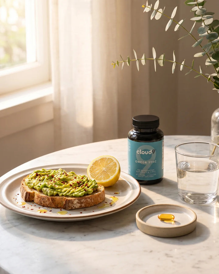 Omega Sync on a breakfast table beside avocado toast, half a lemon and a glass of water